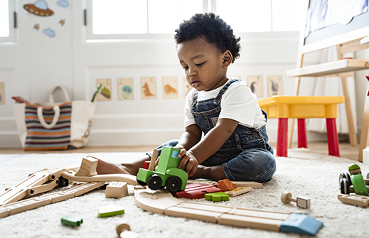 A young child is sitting on the ground playing with his toys
