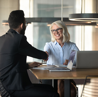 Smiling mature businesswoman shaking hand of young businessman