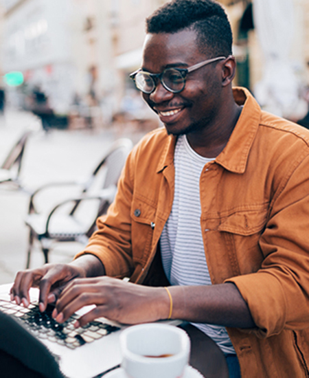 young man on a laptop outside, smiling