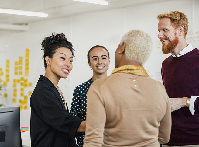 4 colleagues in mid discussion, while standing in an office