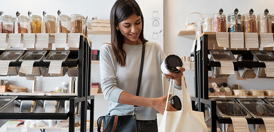 Young woman putting merchandise in reusable shopping bag