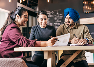 three people sitting in a coffee shop discussing business