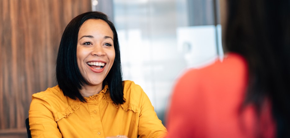 Black woman in a mustard blouse talking