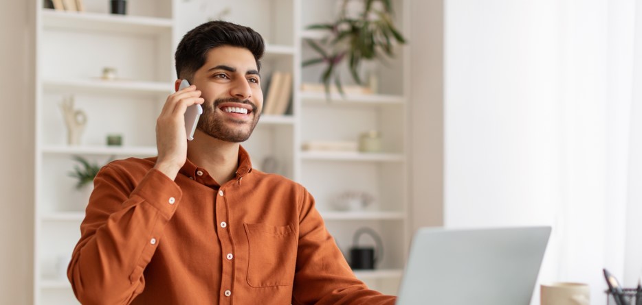 Smiling young man talking on the phone at home