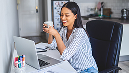woman enjoying a cup of coffee at her laptop
