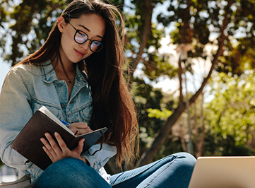 Woman writing in book outdoors